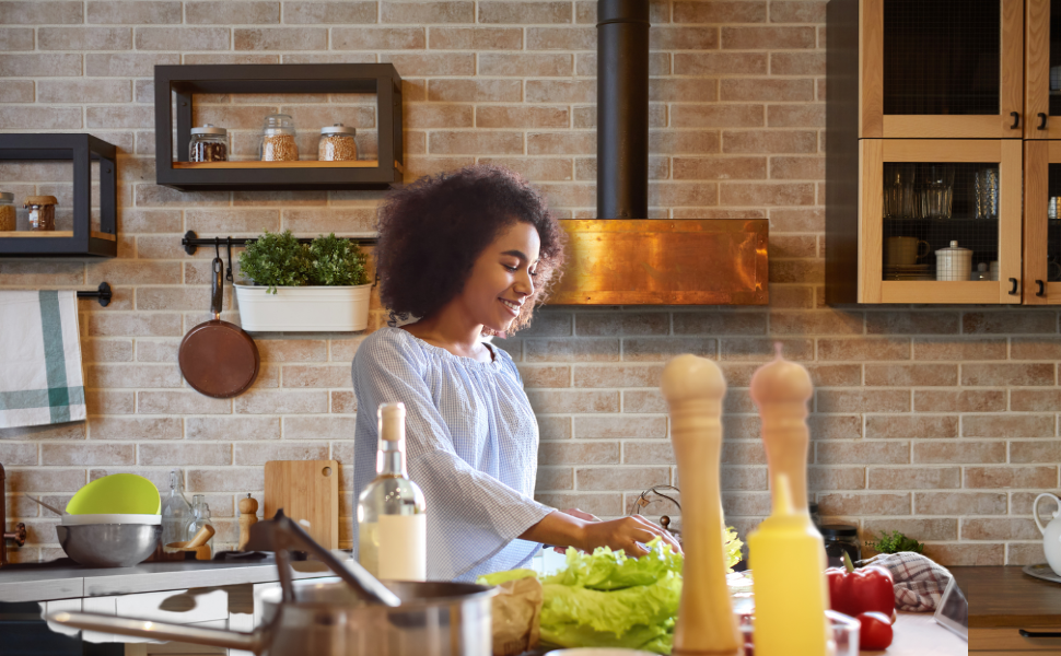 A Black women in a kitchen with brick walls making a salad showing what I eat during my period